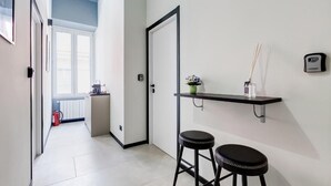 Ein schmales Entree mit einer Tür, einer kleinen Küchenzeile und einem Regal mit Vase und Reed-Diffuser.