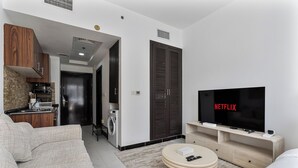 Ein modernes Wohnzimmer mit einer Couch, einem Couchtisch, einem Fernseher und einer Küchenzeile inklusive Waschmaschine.