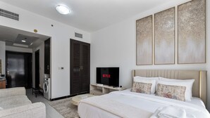 Ein modernes Hotelzimmer mit Bett, Fernseher, Kleiderschrank und einer Sitzecke.