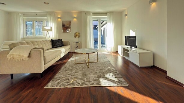 A modern living room with a sofa, coffee table, and TV stand. - Scharnhäusle 2- Large apartment with bathtub & balcony (Ostfildern)