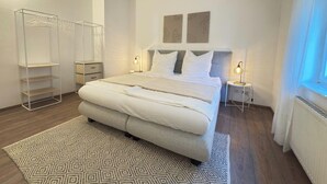 A modern bedroom with a large bed, a wardrobe, and two bedside tables. - Scharnhäusle 2- Large apartment with bathtub & balcony (Ostfildern)