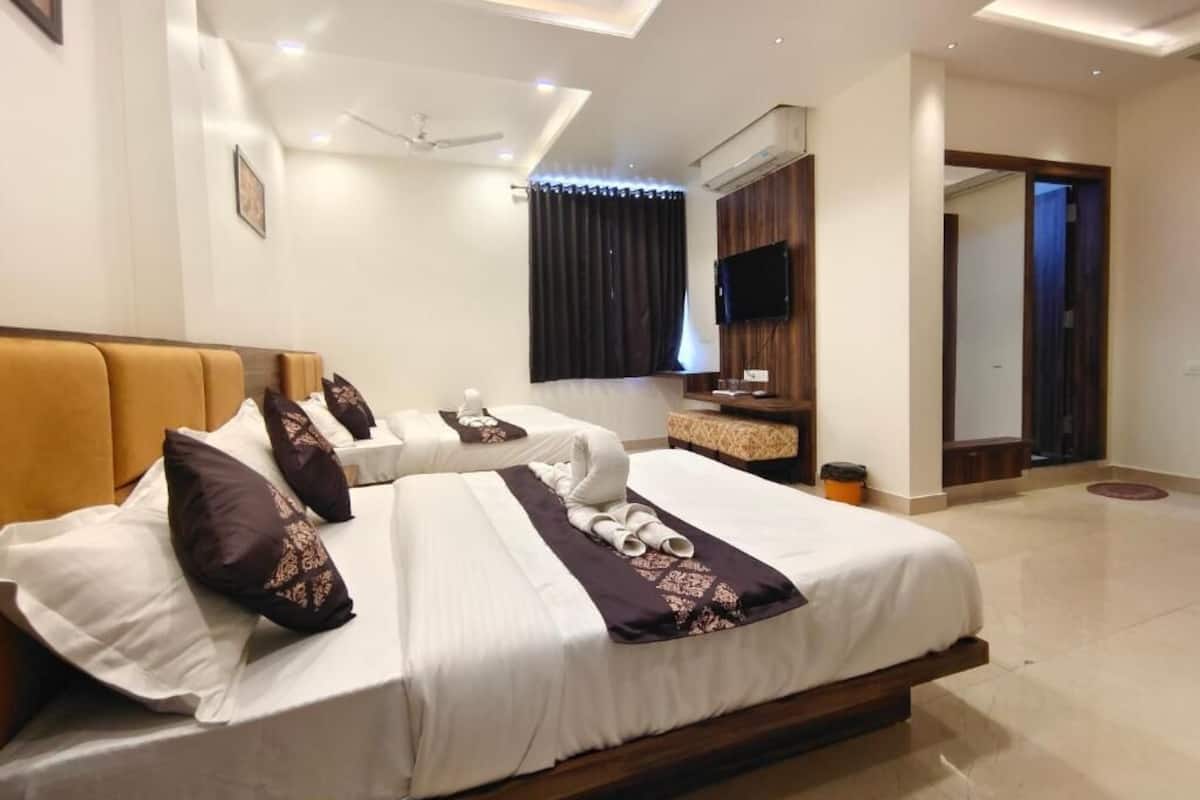 A hotel room with a large bed, a TV mounted on the wall, and a ceiling fan.