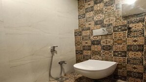 Ein Badezimmer mit Toilette, Dusche und Wandfliesen mit Muster.