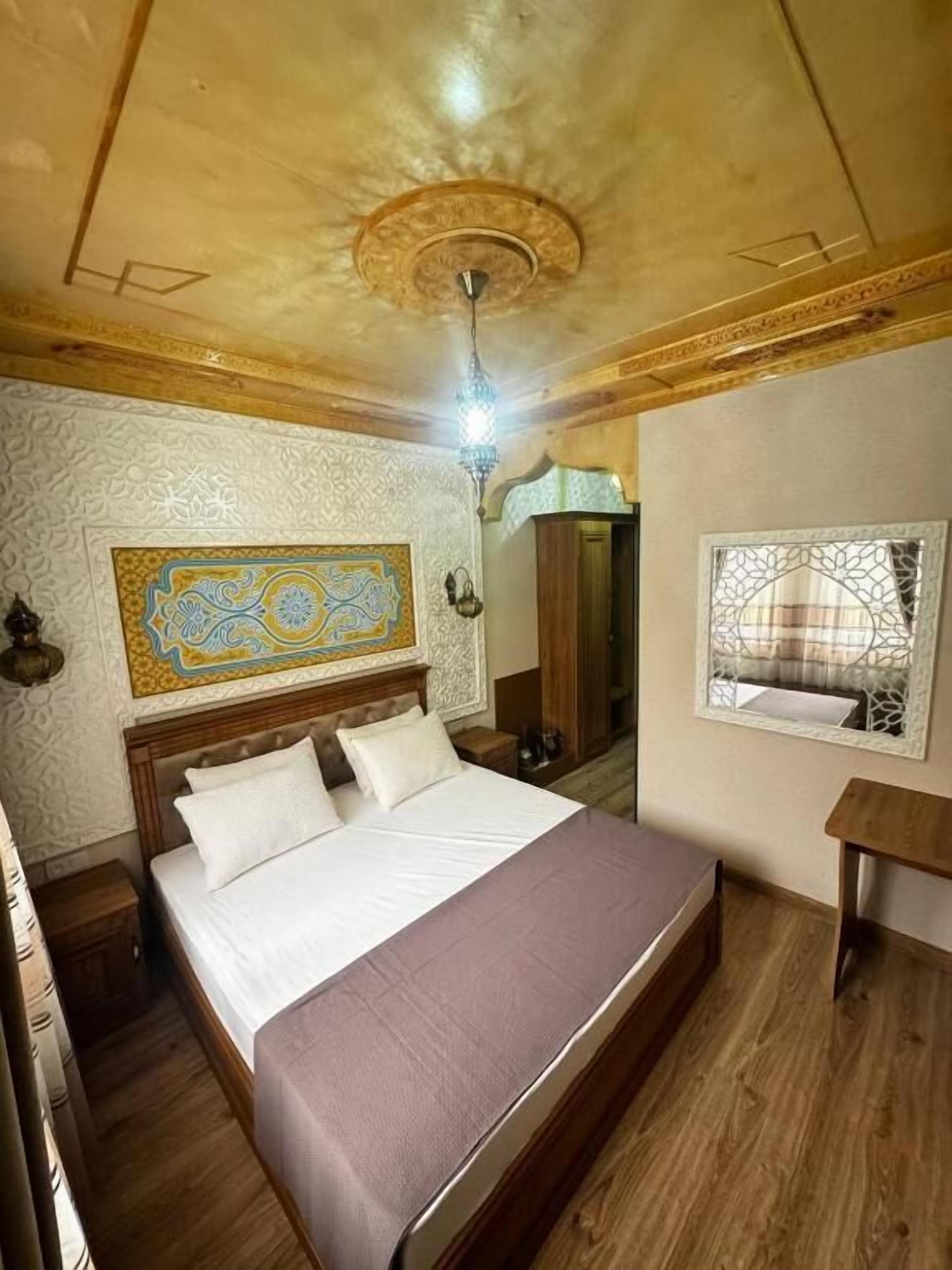 A bedroom with a wooden bed, a nightstand, a mirror, and a ceiling fan.