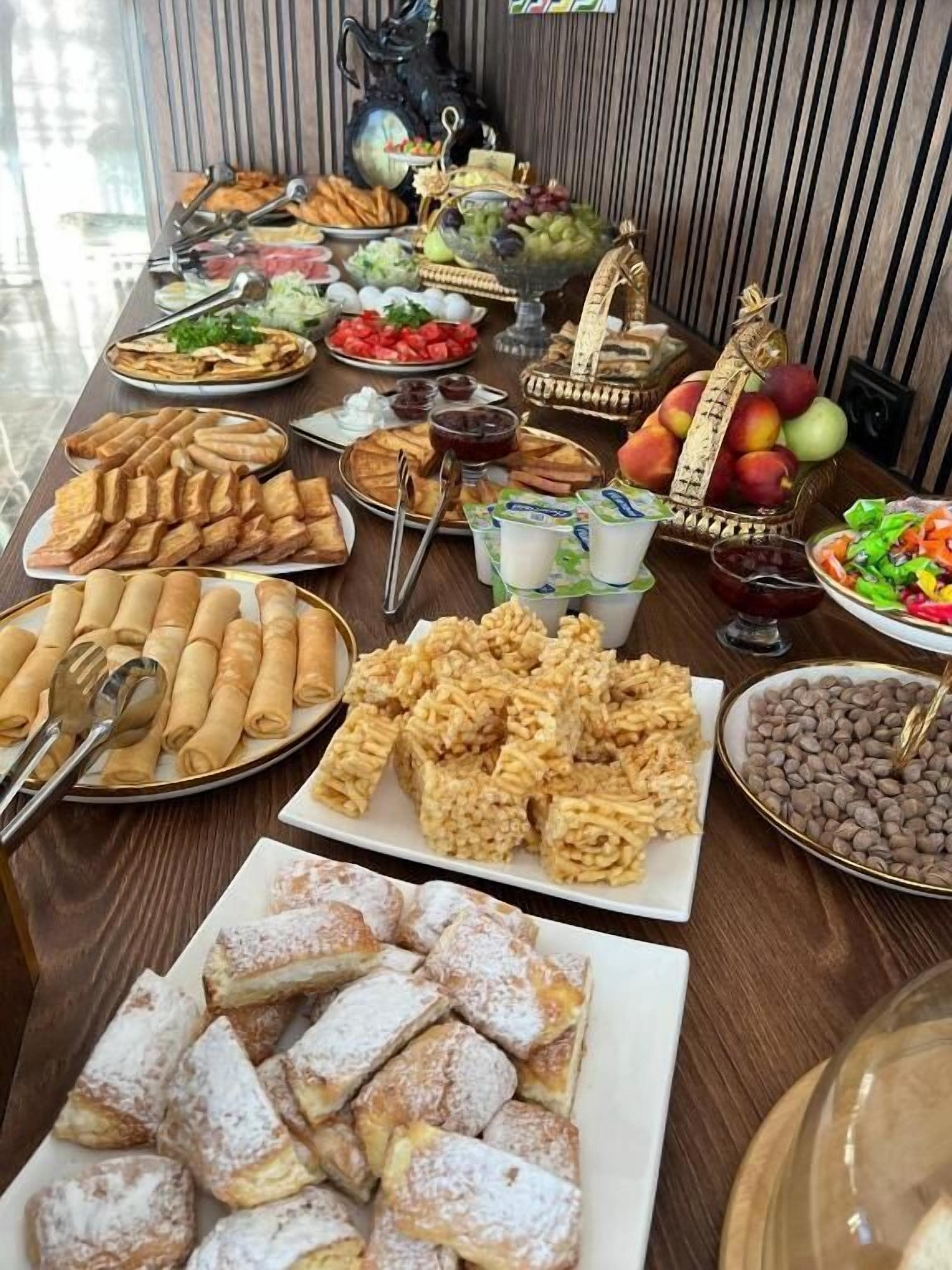 Una mesa de buffet con diversos alimentos, incluyendo pasteles, frutas y postres.