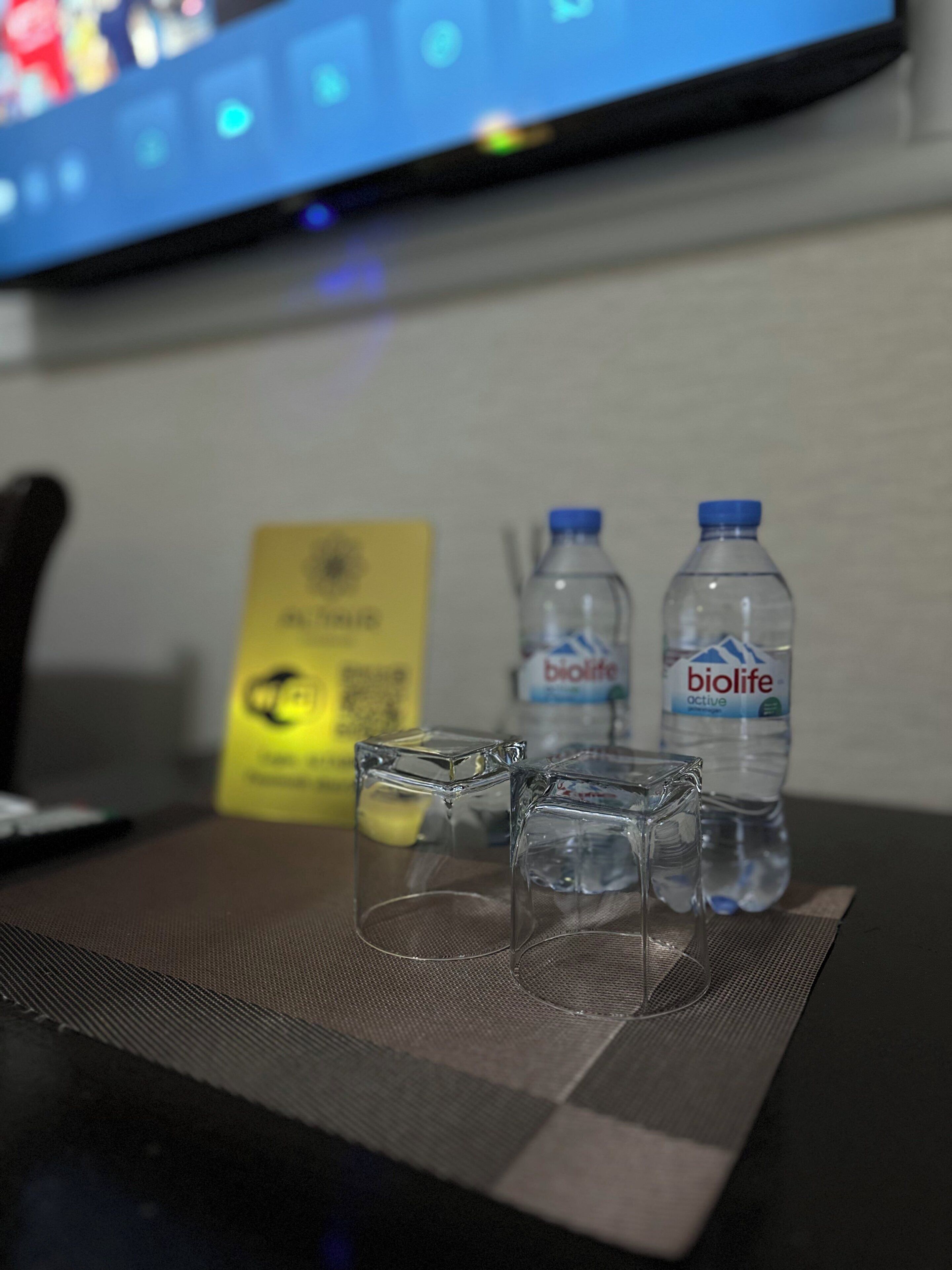 Una mesa con dos botellas de agua, un vaso y un cartel amarillo.