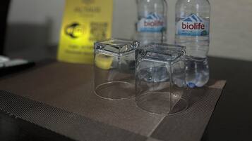 Une table avec deux bouteilles d’eau, un verre et un panneau jaune.