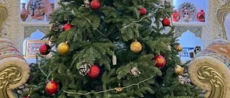 A Christmas tree decorated with ornaments, set against a backdrop of ornate architectural details.