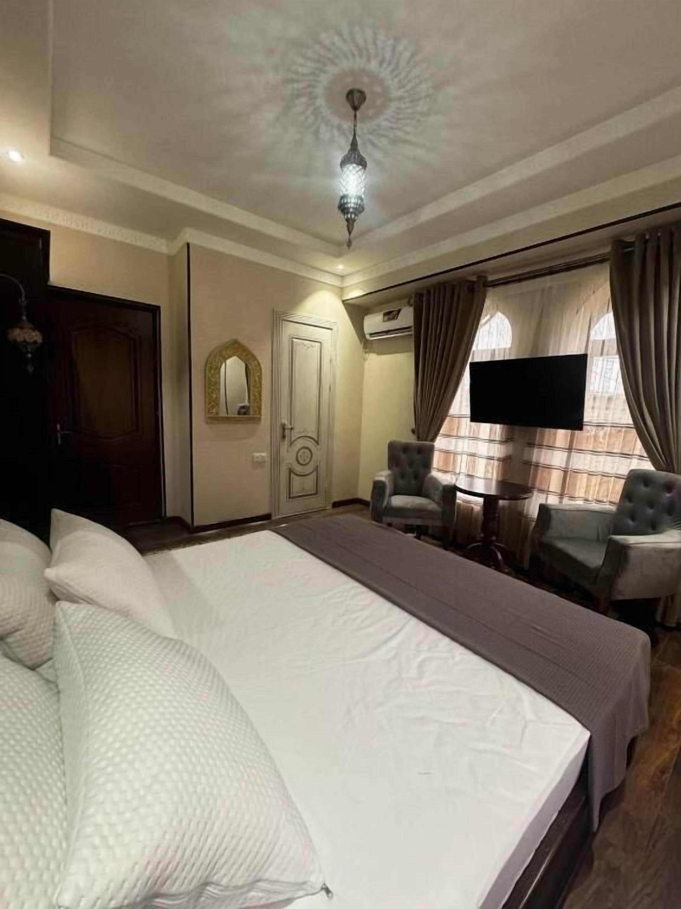 Una habitación de hotel con una cama grande, televisión, escritorio y una silla.