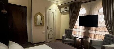 A hotel room with a large bed, a TV, a desk, and a chair.