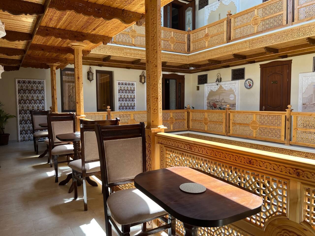 A traditional inn with wooden furniture, a balcony with intricate lattice work, and a tiled floor.
