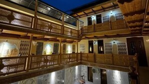 Une cour dotée d’un sol réfléchissant, de balcons en bois et de murs aux motifs décoratifs.