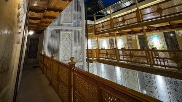 Un couloir orné de balustrades en bois sculptées et d’un mur à motifs.