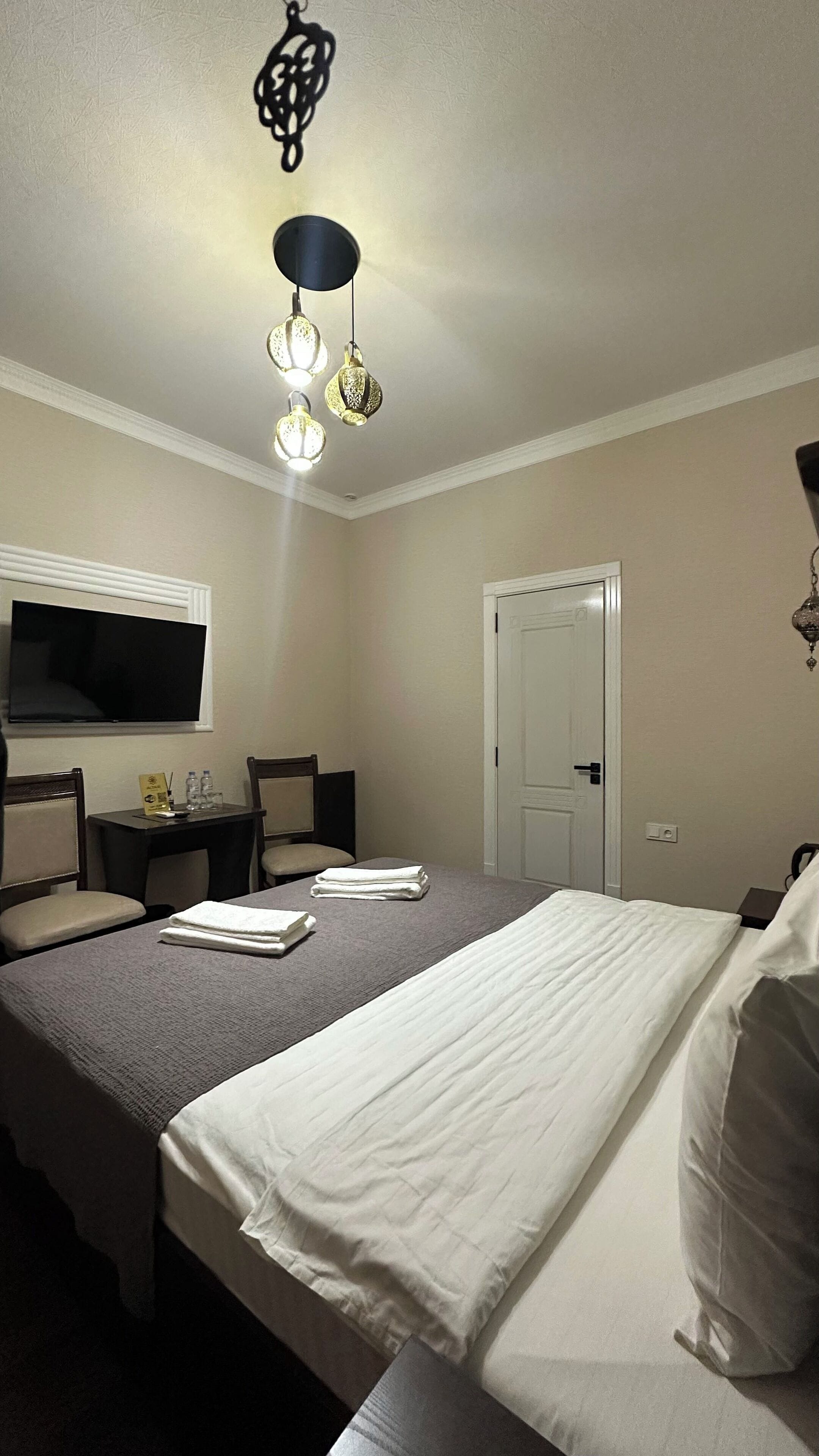 Una habitación de hotel con cama, un escritorio con silla, televisión y puerta.
