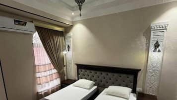 A hotel room with two single beds, a large mirror, a wardrobe, and a decorative wall panel.