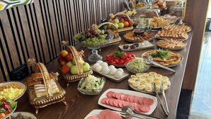 Une table de buffet proposant divers aliments, notamment des fruits, des sandwichs et de la charcuterie.
