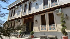 A two-story building with ornate tile work, large windows, and a balcony with outdoor seating. - Altair Boutique (Samarkand)