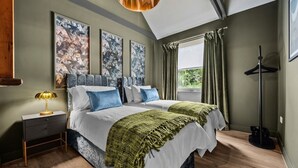 Une chambre avec deux lits, une table de chevet, une lampe sur pied et une fenêtre avec des rideaux.