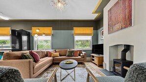 Un salon moderne avec un canapé d’angle, une table basse ronde et une cheminée.