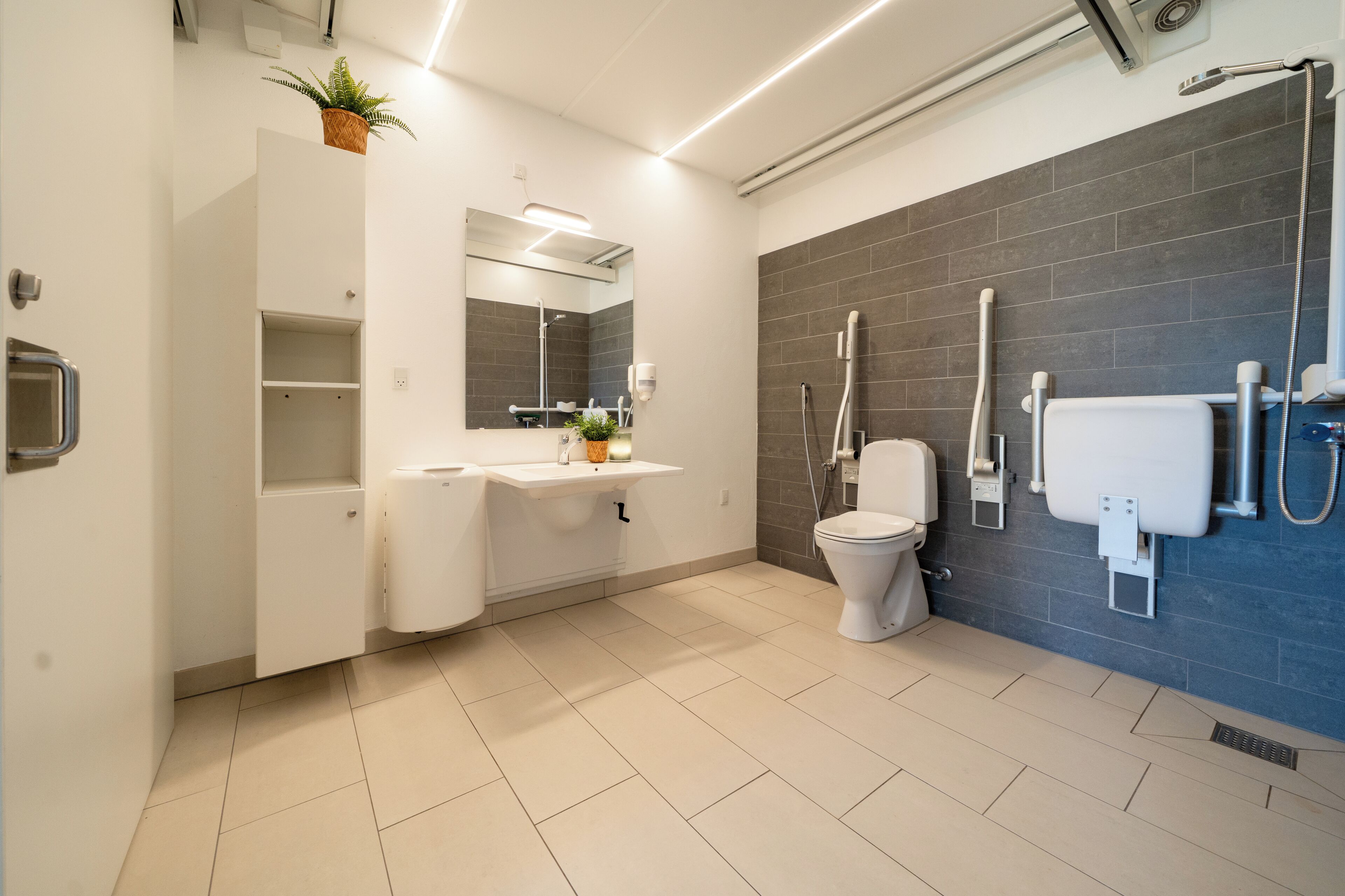 Ein modernes Badezimmer mit Toilette, Waschbecken, Spiegel und Dusche.