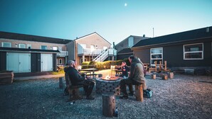 A group of people sitting around a fire pit in an outdoor setting with buildings in the background. - Feriecenter Slettestrand (Fjerritslev)