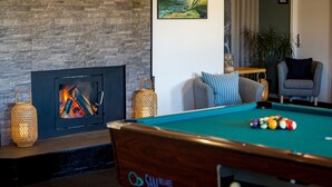 A pool table with balls, a fireplace with logs, and a lounge chair. - Feriecenter Slettestrand (Fjerritslev)