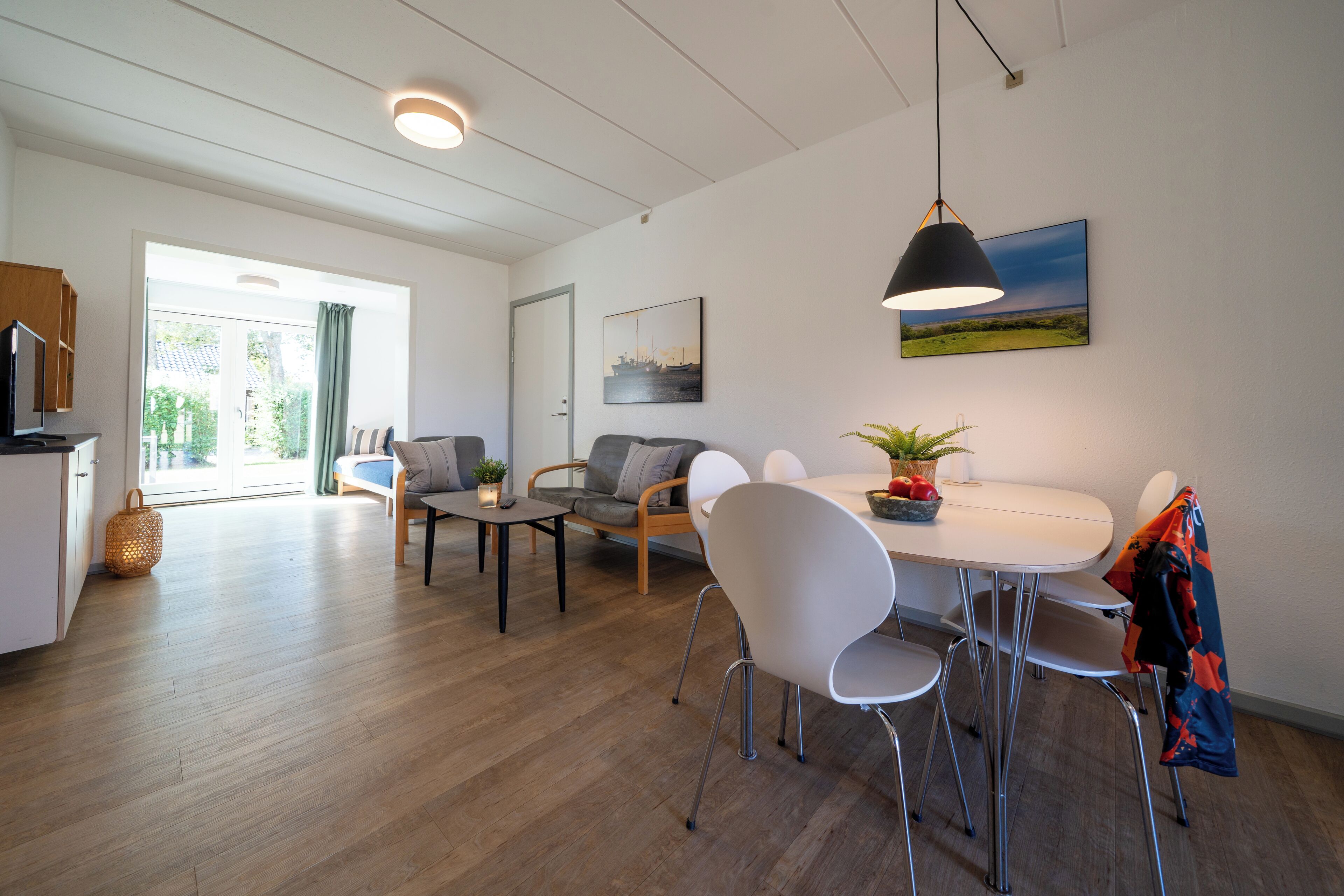 Un salon moderne comprenant une table à manger, des chaises, un canapé et un téléviseur.