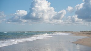 A beach with waves, a clear sky, and distant dunes. - Feriecenter Slettestrand (Fjerritslev)