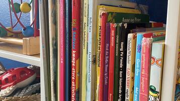 A bookshelf with various books, a woven basket, and a toy car.