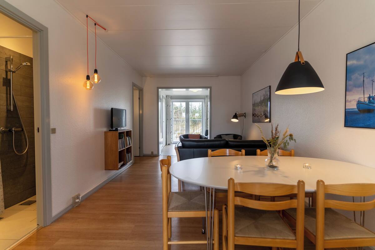 Un espace repas comprenant une table ronde, des chaises et un luminaire suspendu.