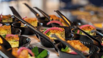 Een buffet met diverse gerechten in zwarte serveerschaalen, gerangschikt op een tafel.