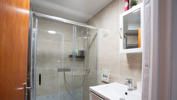 A modern bathroom with a glass-enclosed shower, a white sink, and a mirror above it. - Fulham 6BR 6BA Tube Family London (London)