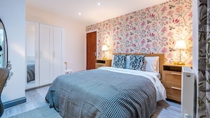 A bedroom with a large bed, two bedside tables with lamps, a wardrobe, and a mirror. - Fulham 6BR 6BA Tube Family London (London)
