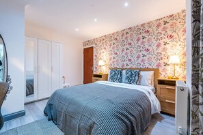 A bedroom with a large bed, two bedside tables with lamps, a wardrobe, and a mirror. - Fulham 6BR 6BA Tube Family London (London)