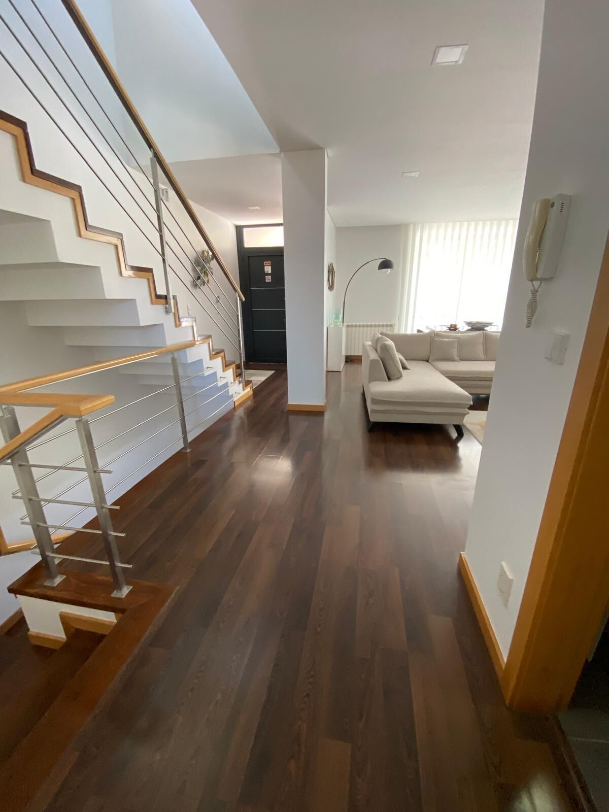 Ein modernes Interieur mit einer Holztreppe, einem Wohnbereich mit einer Couch und einem Esstisch.