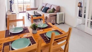 Un salon moderne avec un coin repas, comprenant un ensemble de canapés, une table à manger avec des chaises et une grande fenêtre laissant entrer la lumière naturelle.