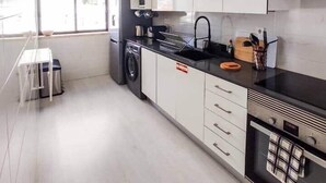 Une cuisine moderne avec des armoires blanches, un plan de travail noir et un four encastré.