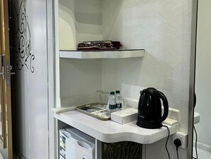 A small kitchenette with a coffee maker, water bottles, and a tray with utensils. - Monatana Golden Hotel (Makkah)