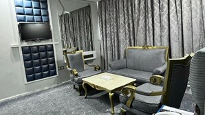 Una sala de estar moderna con un sofá, sillones, una mesa de centro y un televisor de pantalla plana montado en la pared.