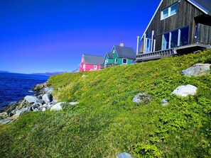 A coastal house with a wooden exterior and a balcony overlooking the sea. - Hotel Aurora (Nuuk)