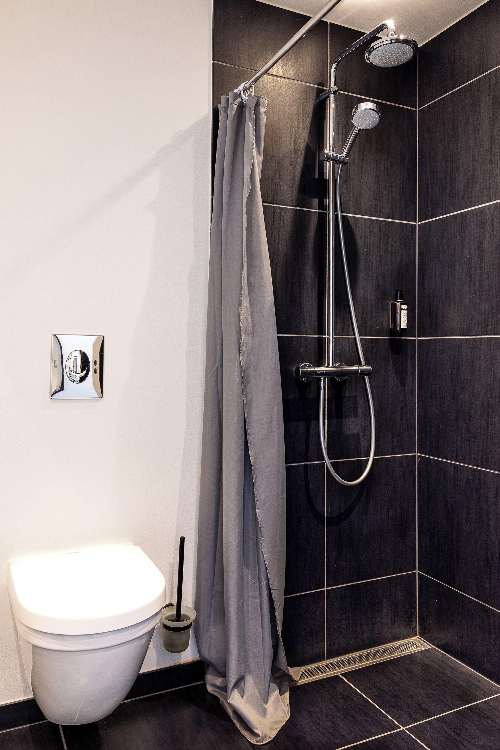 Un baño moderno con inodoro, ducha y panel de control.