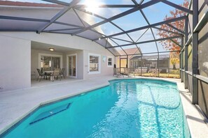 Uma piscina com cobertura de vidro, área de estar com cadeiras e vista para o exterior.