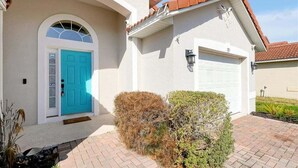 Een gelijkvloers huis met een witte gevel, een blauwe deur en een garage.