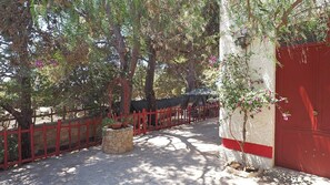 A pathway lined with trees and a red fence, leading to a building with a red door. - Villa Leda in Marina di Mancaversa (Taviano)