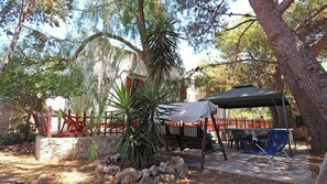 An outdoor patio area with a covered table and chairs, a stone wall, and a palm tree. - Villa Leda in Marina di Mancaversa (Taviano)