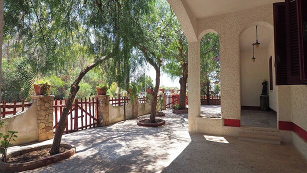 A covered outdoor area with a stone wall, red fence, and potted plants. - Villa Leda in Marina di Mancaversa (Taviano)