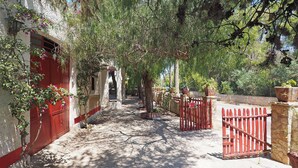 A narrow pathway flanked by red gates and white walls, leading to a building entrance. - Villa Leda in Marina di Mancaversa (Taviano)
