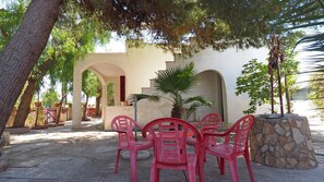 A patio with a table and chairs, a palm tree, and a stone wall. - Villa Leda in Marina di Mancaversa (Taviano)
