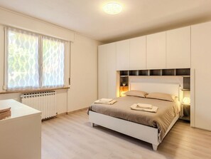 A bedroom with a bed, bedside tables, a radiator, and a window with sheer curtains. - Lovely apartment for 4 people with WIFI, TV and balcony (Varenna)