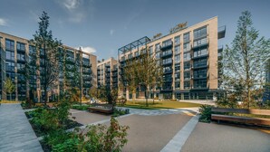 A modern multi-story residential building with balconies, a central courtyard with benches, and surrounding greenery. - Coopers Cross Two by Dublin At Home (Dublin)